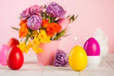 Bahar çiçeklerinin arka planında Paskalya renkli yumurtalar. Parlak Paskalya konsepti. Boşluğu kopyala.