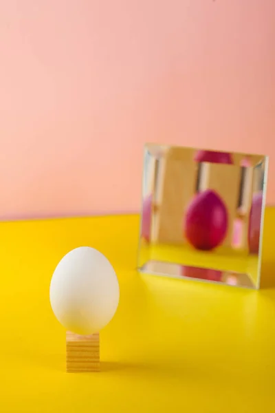 Easter concept, Easter egg decoration. White egg, in the mirror displaying a colored Easter egg. Copy space.