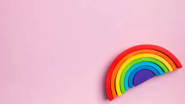 Pembe arka planda parlak tahta gökkuşağı oyuncağı, Montessori materyal konsepti, erken çocuk gelişimi. Boşluğu kopyala.