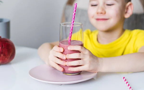 Un chico lindo tiene un vaso de batidos de bayas en sus manos. El concepto de comida saludable. Copiar espacio. —  Fotos de Stock