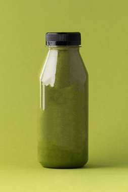 Yeşil arka planda, şişede yeşil meyve püresi. Sağlıklı beslenme kavramı. Boşluğu kopyala.