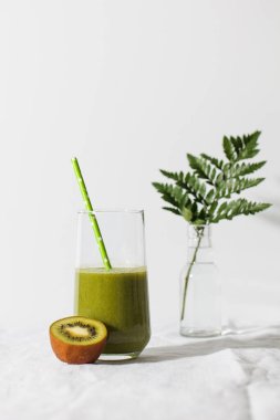 Pipetle bardakta yeşil smoothie ve arka planda kivi. Sağlıklı beslenme kavramı. Boşluğu kopyala.