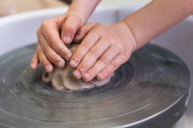 Bir çocuk çömlekçi çarkında kil ile çalışır. Yaratıcı çocuk atölyesi konsepti.