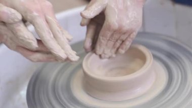 Usta çömlekçi çocuğa çömlekçi çarkında çamurla çalışmayı öğretir..