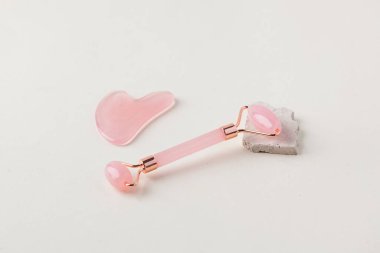 Rose Quartz gua sha stone, arka planda yeşim taşı. Evde cilt bakımı kavramı. Boşluğu kopyala.