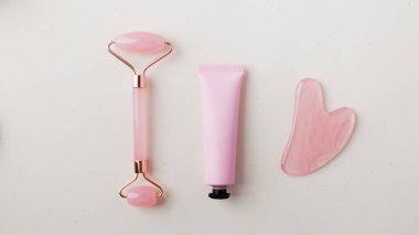 Gül kuvars guasha taşı, yeşim taşlı ve yüzü nemlendirici kozmetik ürünlü pembe tüp. Cilt bakımı