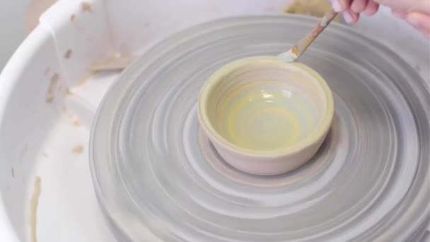 Painting a clay plate on a rotating potters table with paints on wet clay — Stock Video