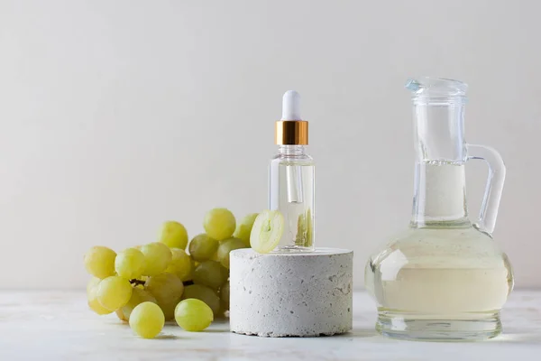 Přírodní hroznový olej ve skleněné kapátko láhev a džbán na světlém pozadí — Stock fotografie