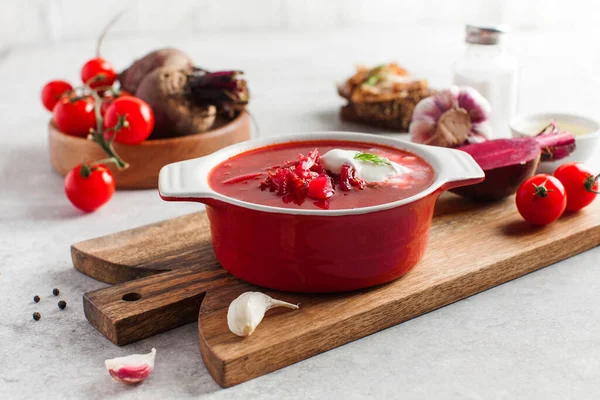 Delicious fresh red borscht, garlic, tomatoes and beets on the kitchen table. — Stock Photo, Image