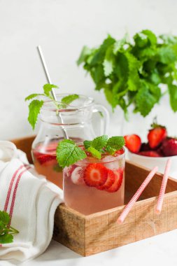 Sürahi ve bardakta ev yapımı taze çilekli limonata.