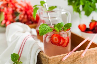 Sürahi ve bardakta ev yapımı taze çilekli limonata.