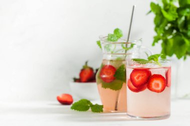 Bardakta taze çilekli limonata ve taze çilek ve nane yapraklı sürahi. Yaz içeceği 