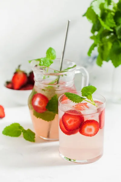 Zelfgemaakte verfrissende aardbeienlimonade in glas en kan met verse aardbeien en muntblaadjes. Zomer drankje — Stockfoto