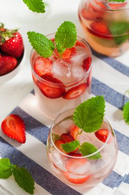 Ev yapımı taze çilekli limonata bardakta ve taze çilek ve nane yapraklı sürahi. Yaz içeceği 