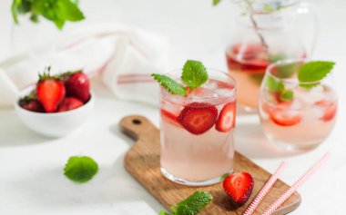 Ev yapımı taze çilekli limonata bardakta ve taze çilek ve nane yapraklı sürahi. Yaz içeceği 