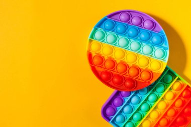 Sarı arka planda oyuncak silikon kullan. Stres önleyici oyuncaklar, çocuk oyuncaklarında moda. Boşluğu kopyala.