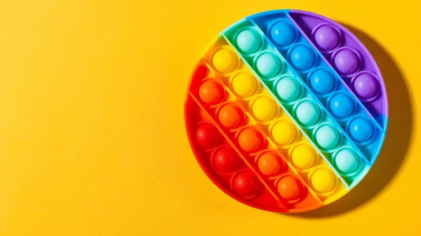 Pop-lo silicone de brinquedo em um fundo amarelo. Brinquedo anti-stress, uma tendência em brinquedos infantis. Espaço de cópia. — Fotografia de Stock