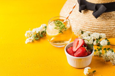 Yaz dönemi. Hasır şapka, ferahlatıcı limonata, olgun çilekler bir kasede. Boşluğu kopyala.