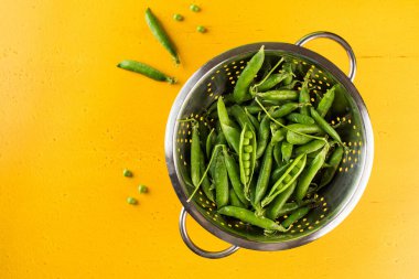 Sarı arka planda taze taze taze bezelyeler. Boşluğu kopyala.