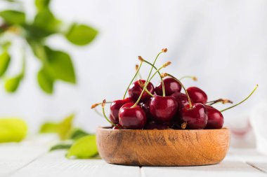 Ahşap bir arka planda, ahşap bir kasede sulu kiraz meyveleri..