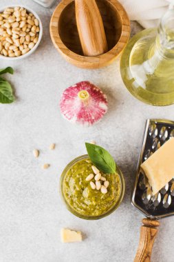 Kavanozda pesto sosu, bir parça parmesan peyniri, fesleğen yaprağı, çam fıstığı ve zeytinyağı. Boşluğu kopyala.