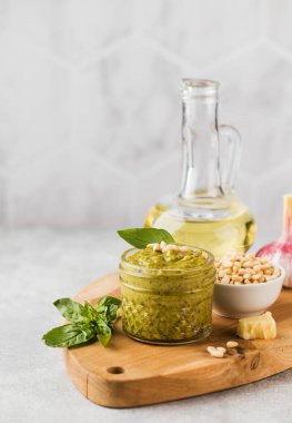 Yeşil fesleğen yapraklı pesto sosu, parmesan peyniri dilimleri ve tahta tahtada bir sürahi zeytinyağı. İtalyan mutfağı