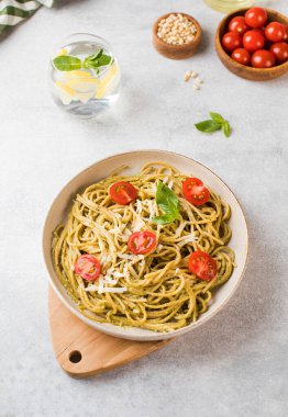 Pesto soslu spagetti makarna ve tabakta vişneli domates. Menü, İtalyan mutfağı..