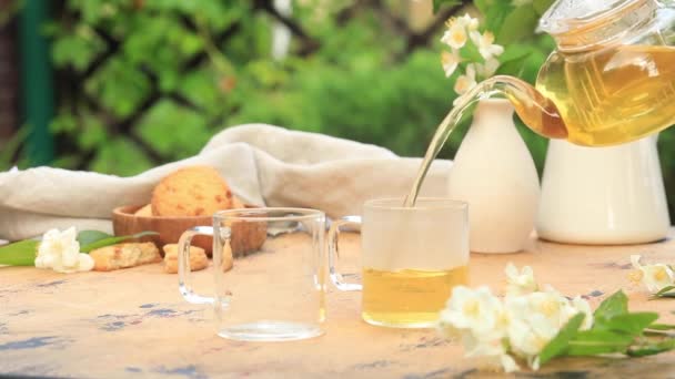Groene thee met jasmijn wordt uit een theepot in mokken gegoten. — Stockvideo