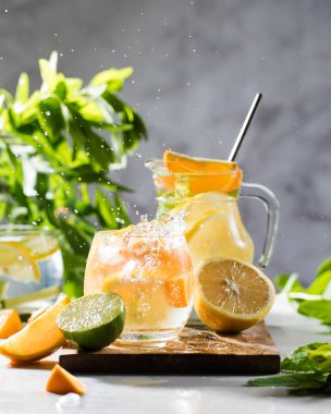 Limonata limonata ve naneli sürahi ve bardakta su sıçraması. Yaz içkileri. Boşluğu kopyala.