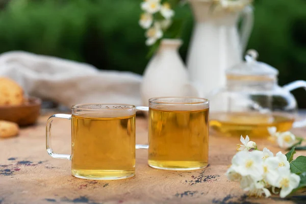 Teh Cina hijau dengan melati di cangkir dan poci teh di atas meja kayu dengan bunga melati. — Stok Foto