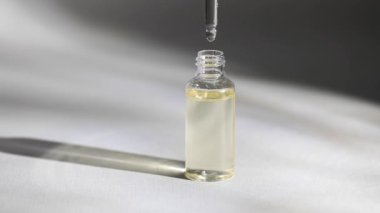 Cam düşürücü şişenin maketi. Kozmetik pipetinden yağlı bir damla düşüyor.