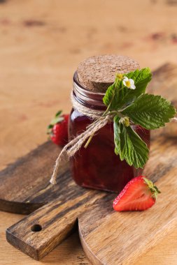 Tahta bir tahtanın üstünde kavanozda çilek reçeli. Fermente edilmiş çilek.