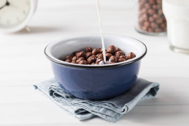 Süt yuvarlak kakao taneleriyle bir tabağa dökülür. Kuru kahvaltı..