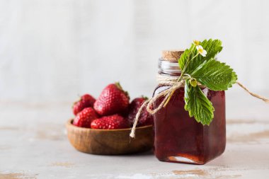 Tahta bir tahtanın üstünde kavanozda çilek reçeli. Fermente edilmiş çilek.