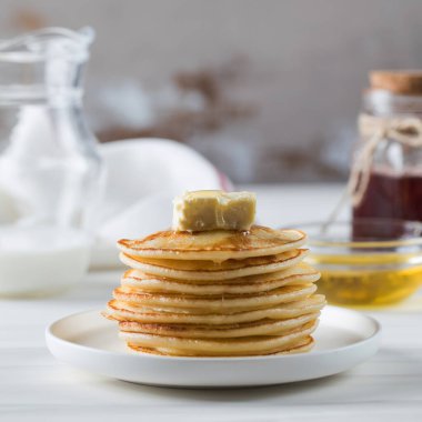 Krepler bir parça tereyağı ile bir tabakta istiflenmiş ve bal sosuyla ıslatılmış. Kahvaltı konsepti.