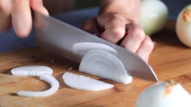 Şef tahtanın üzerinde bir bıçakla beyaz soğan keser..