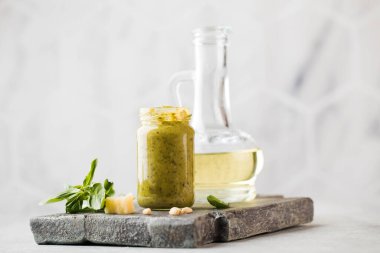 Yeşil fesleğen yapraklı pesto sosu, parmesan peyniri dilimleri ve tahta tahtada bir sürahi zeytinyağı. Boşluğu kopyala.