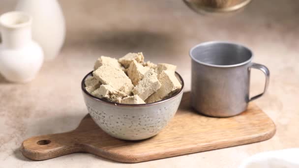 Kaffee wird in einen Becher aus Turki gegossen, neben einer Schüssel mit Halva-Scheiben. — Stockvideo