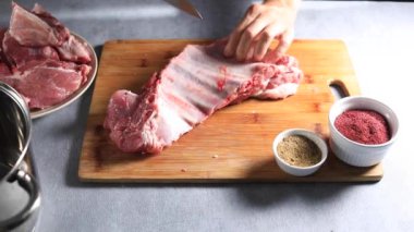 Şef domuz kaburgalarını tahta bir tahtanın üzerinde bıçakla parçalara ayırıyor.