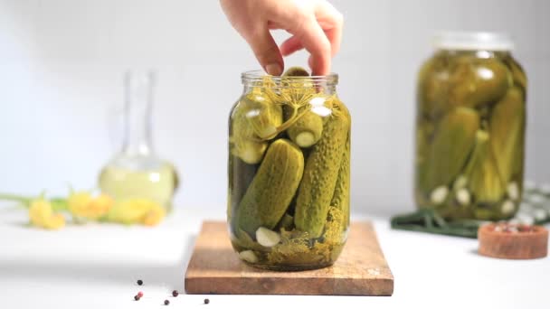 A womans hand takes out a pickled cucumber from a jar. Slow motion — стоковое видео