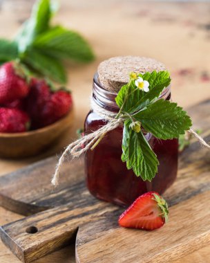 Tahta bir tahtanın üstünde kavanozda çilek reçeli. Fermente edilmiş çilek.
