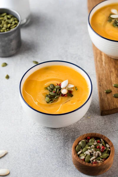 Sup krim labu dalam mangkuk dengan biji di latar belakang abu-abu. Menunggang dengan nyaman, menu musim gugur. — Stok Foto
