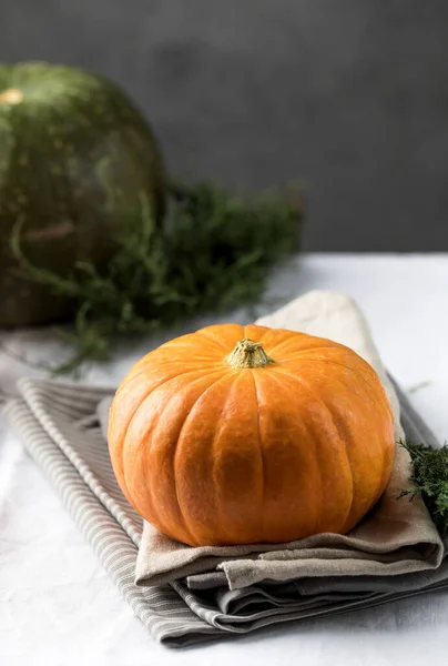 Una calabaza redonda naranja sobre un mantel de lino. El concepto de otoño, cosecha. —  Fotos de Stock