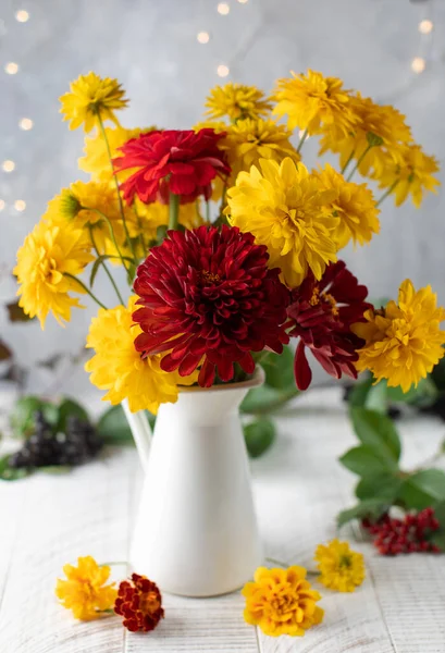 白色桌子上的酒壶里放着一束红黄相间的花.秋假的概念. — 图库照片