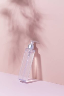 Pembe arka planda gölgeli bir kozmetik ürününün maketi. Yüz için temizleyici tonik, mikiler suyu.. 