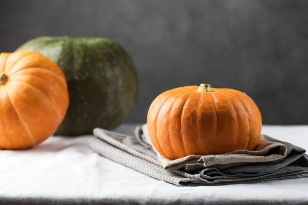 Uma abóbora redonda cor de laranja em uma toalha de mesa de linho. O conceito de outono, colheita. — Fotografia de Stock