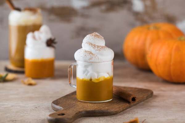 Pumpkin latte with whipped cream in a glass on the background of pumpkins.