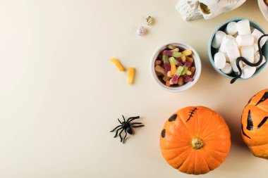 Tatlı ikramlı Cadılar Bayramı tasarımı korkunç yüzlü balkabakları ve bej arka planda kopyalama alanı 