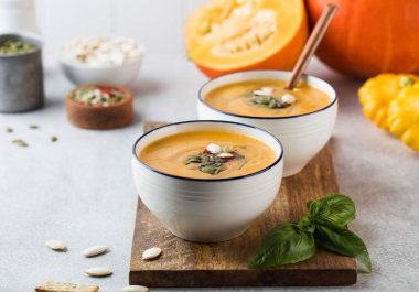 Tahtaya serpiştirilmiş iki kase balkabağı kremalı çorba. Sonbahar çorbası.