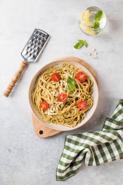 Pesto soslu spagetti makarna ve kiraz domatesleri, bir bardak su. Üst görünüm